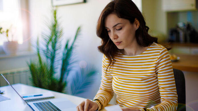 woman sitting at table with phone and laptop