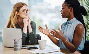 Two diverse businesswomen having a discussion to share ideas and plans while working together in an office