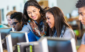 Teacher helping students on computers