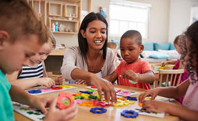 Teacher And Pupils Using Flower Shapes In Montessori School