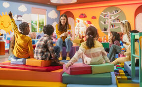 Cheerful Preschool Educator Playing and Creatively Studying with Multiethnic Kids in Kindergarten. Small Adorable Children Getting Basic Reading and Writing Skills, Learning Alphabet