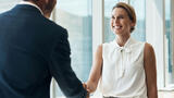 two businesspeople shaking hands in a corporate setting.