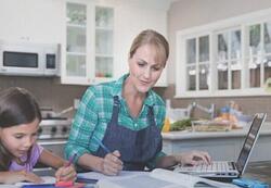 female_student_and_daughter_studying_at_table_in_kitchen