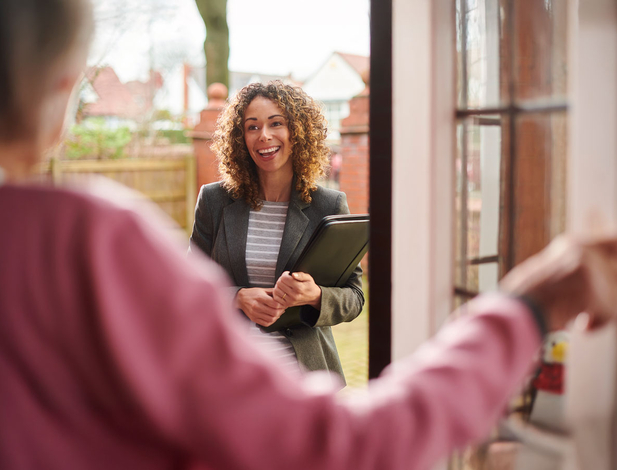 Social worker at the door talking to elderly lady