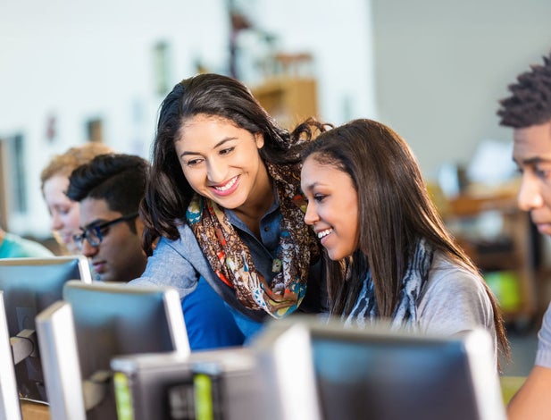 Teacher helping students on computers