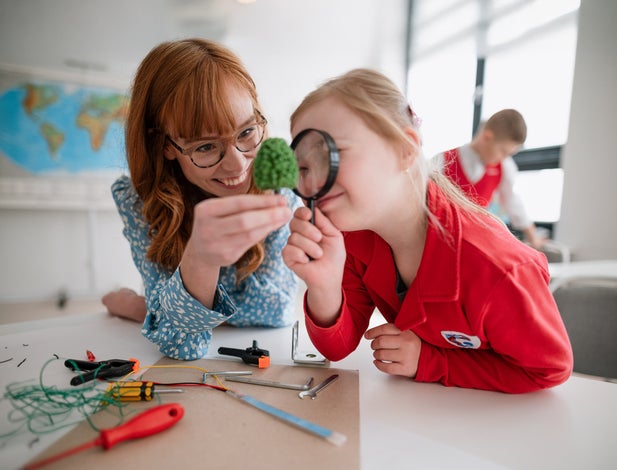 A little student with Down syndrome with tutor teacher programming electric toys and robots at robotics classroom