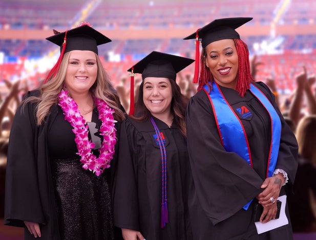 Three graduates posing at commencement