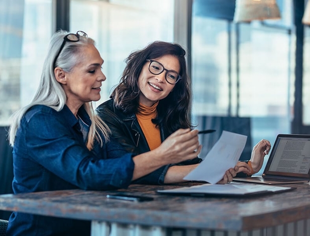 female mentor helping young asian female coworker
