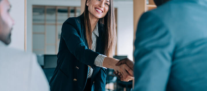 Business people shaking hands in the office. Group of business persons in business meeting. Three entrepreneurs on meeting in board room. Corporate business team on meeting in modern office. Female manager discussing new project with her colleagues. Company owner on a meeting with two of her employees in her office.