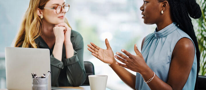 Two diverse businesswomen having a discussion to share ideas and plans while working together in an office