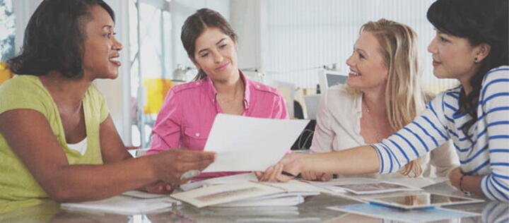 four female project management students sitting at a table discussing work