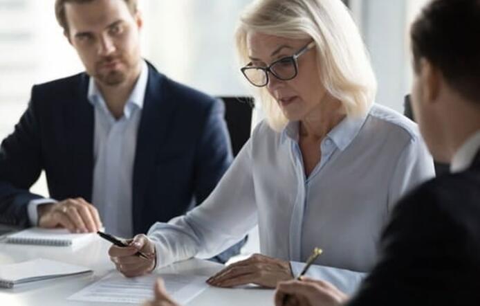 A business woman reviewing documents with two subordinates.