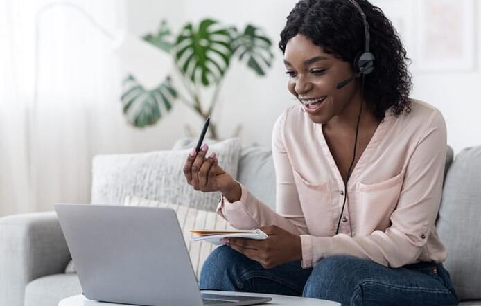 young female student interacting on laptop with headset on