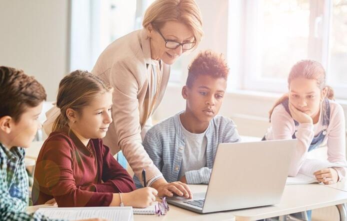 older female teacher who has her credential teaching a group of older elementary school children