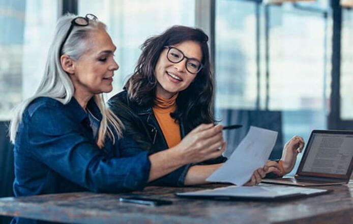 older female business women mentoring younger asian female at informal location
