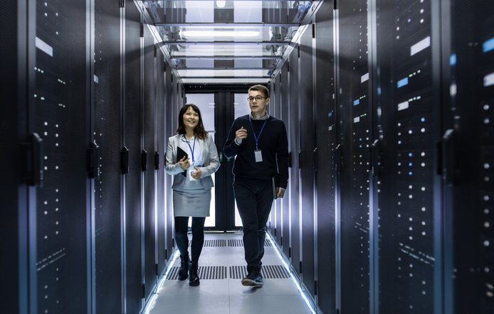 a male and female IT personnel walking through a computer/server room