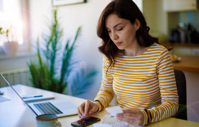 woman sitting at table with phone and laptop