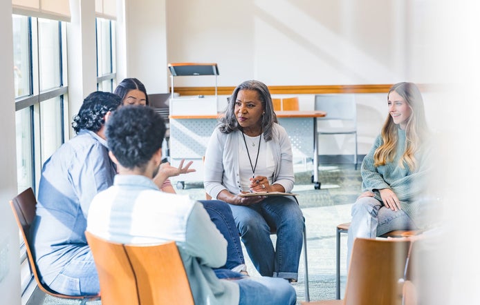 Female social worker sitting in a group setting listening to conversation