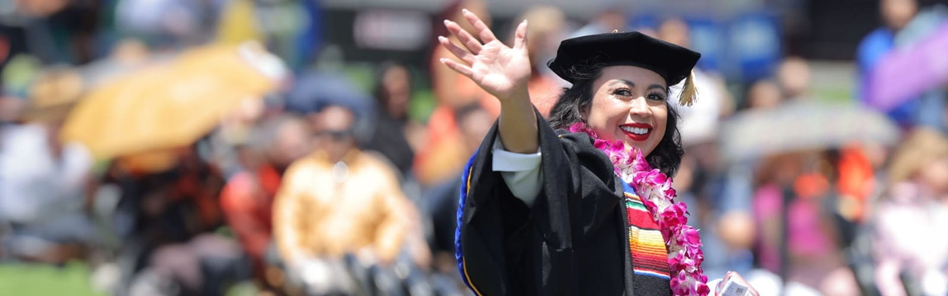 Hispanic female doctoral student from UMass Global at commencement waiving
