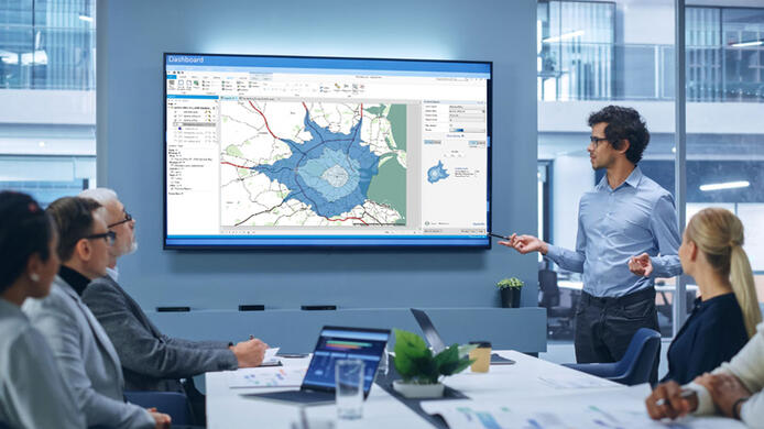 Office Conference Room Meeting Presentation: Latin Businessman Talks, Uses Wall TV to Show Company Growth with Big Data Analysis, Graphs, Charts, Infographics. Multi-Ethnic e-Commerce Startup Workers