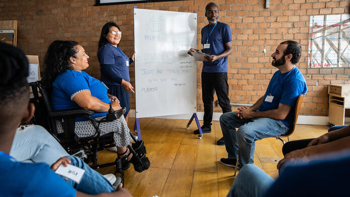 Mature man talking in a meeting at a community center - including a disabled person