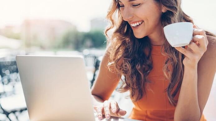 woman on her laptop at a cafe drinking coffee outdoors