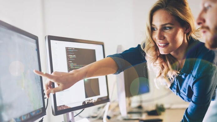 manager showing IT professional an item on a desktop screen