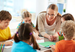 Portrait of diligent schoolkids and their teacher talking at lesson