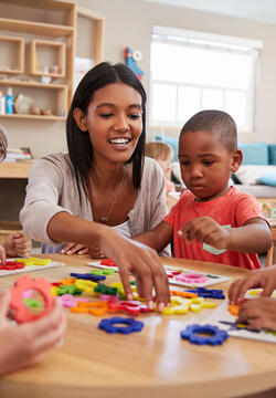 Teacher And Pupils Using Flower Shapes In Montessori School