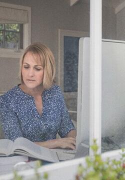 female_studying_with_textbook_and_laptop_in_room