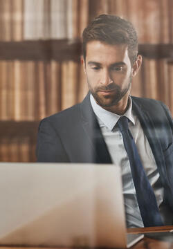legal_studies_paralegal_800x600 man working on a computer in a paralegal job with books behind him