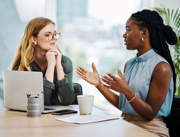 Two diverse businesswomen having a discussion to share ideas and plans while working together in an office
