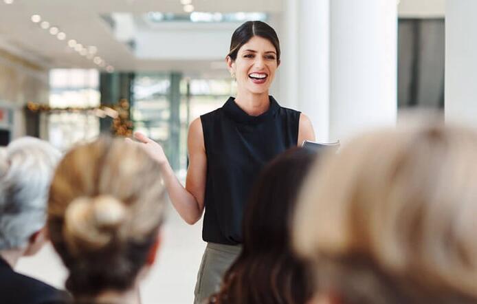 confident woman leader speaking to a group of coworkers